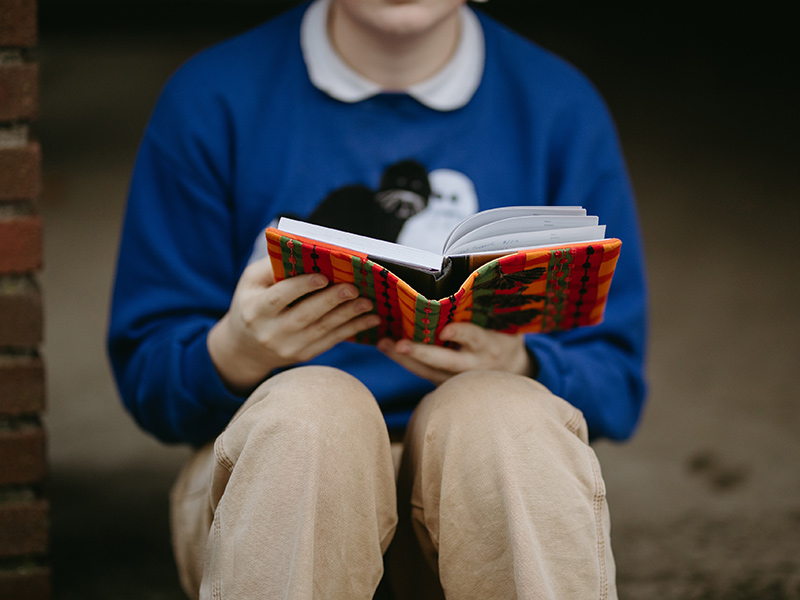 A Reed Student holds a book that has a reusable fabric book cover