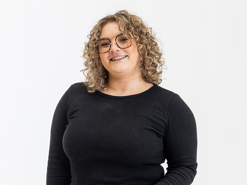 A portrait of Alyssa Gorkin wearing glasses and a long-sleeved black shirt.