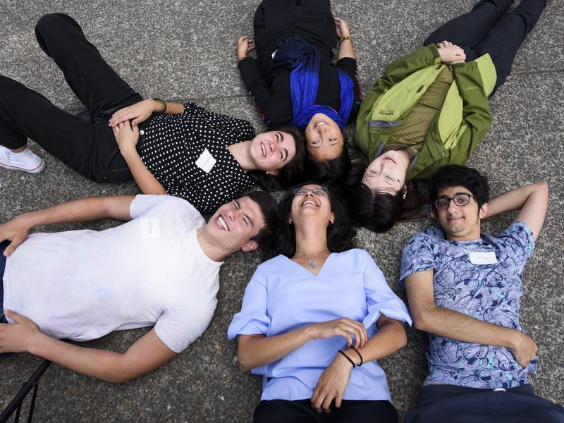 Students lie on the ground in a circle with their heads nearly touching.
