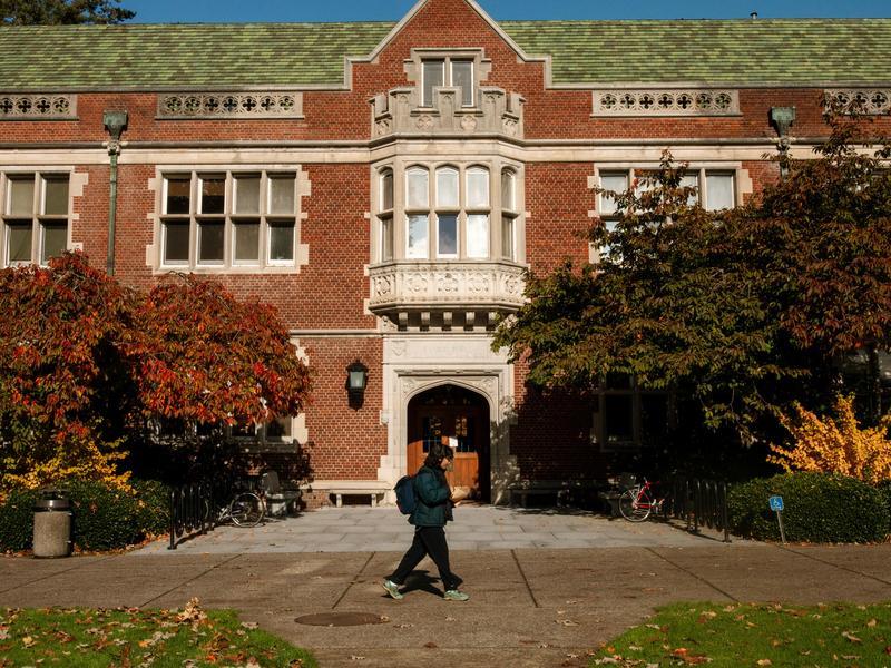A student walks on the sidewalk outside of Eliot Hall.
