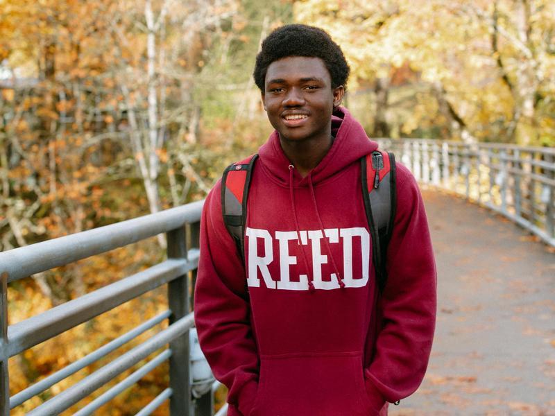 A student wearing a red Reed sweatshirt walks across the Blue Bridge.